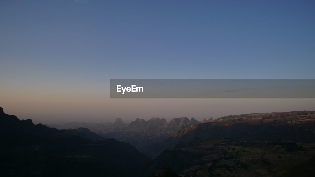 SCENIC VIEW OF SILHOUETTE MOUNTAINS AGAINST SKY AT SUNSET