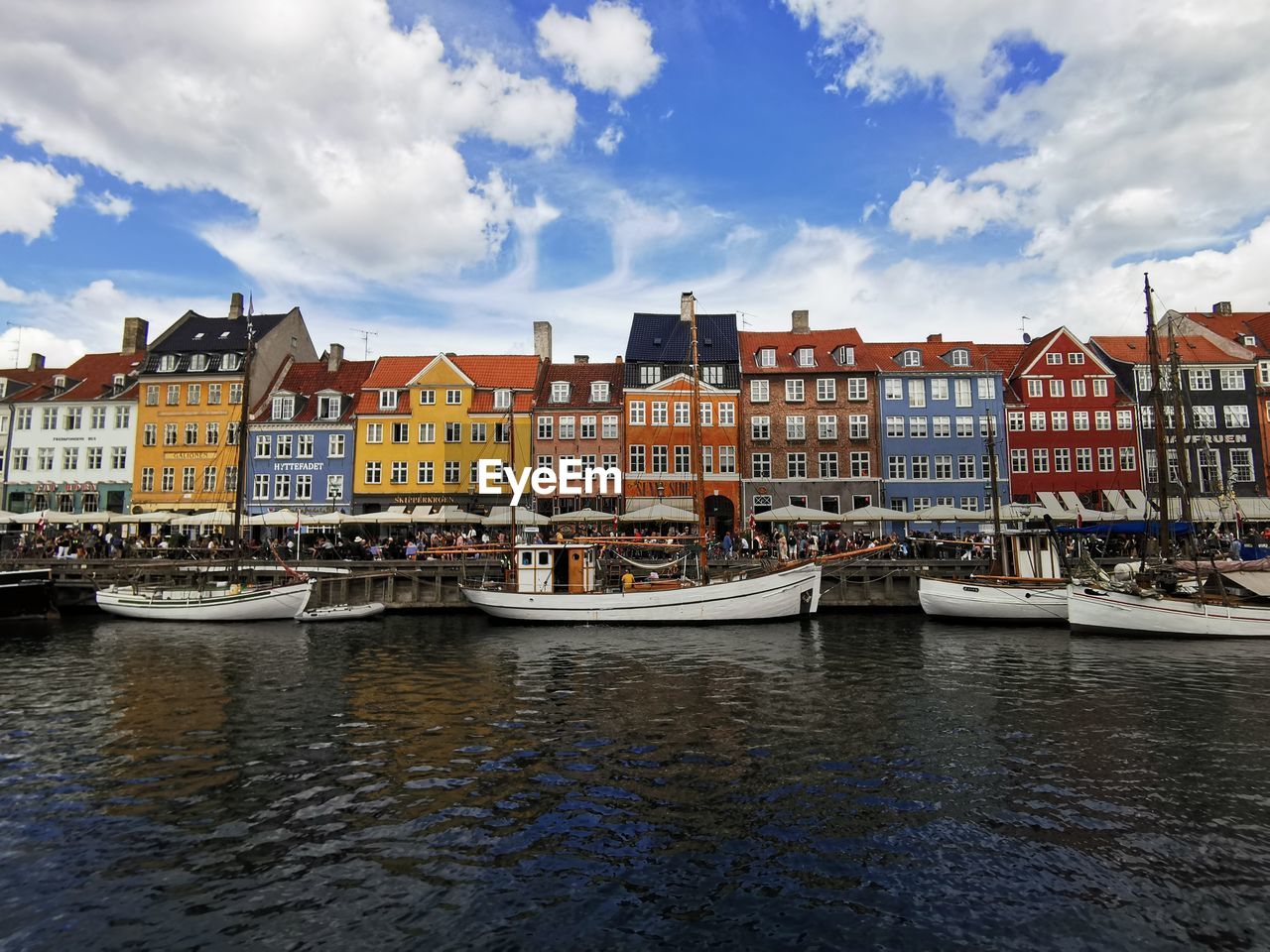 Buildings by river against sky