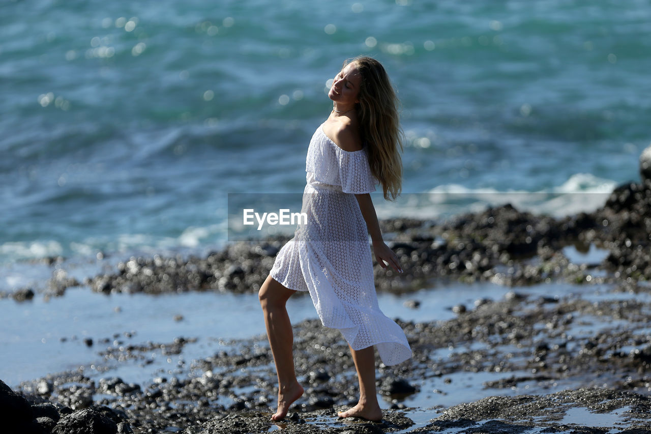 WOMAN STANDING AT BEACH