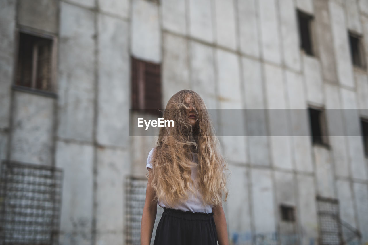 Low angle view of girl standing against building