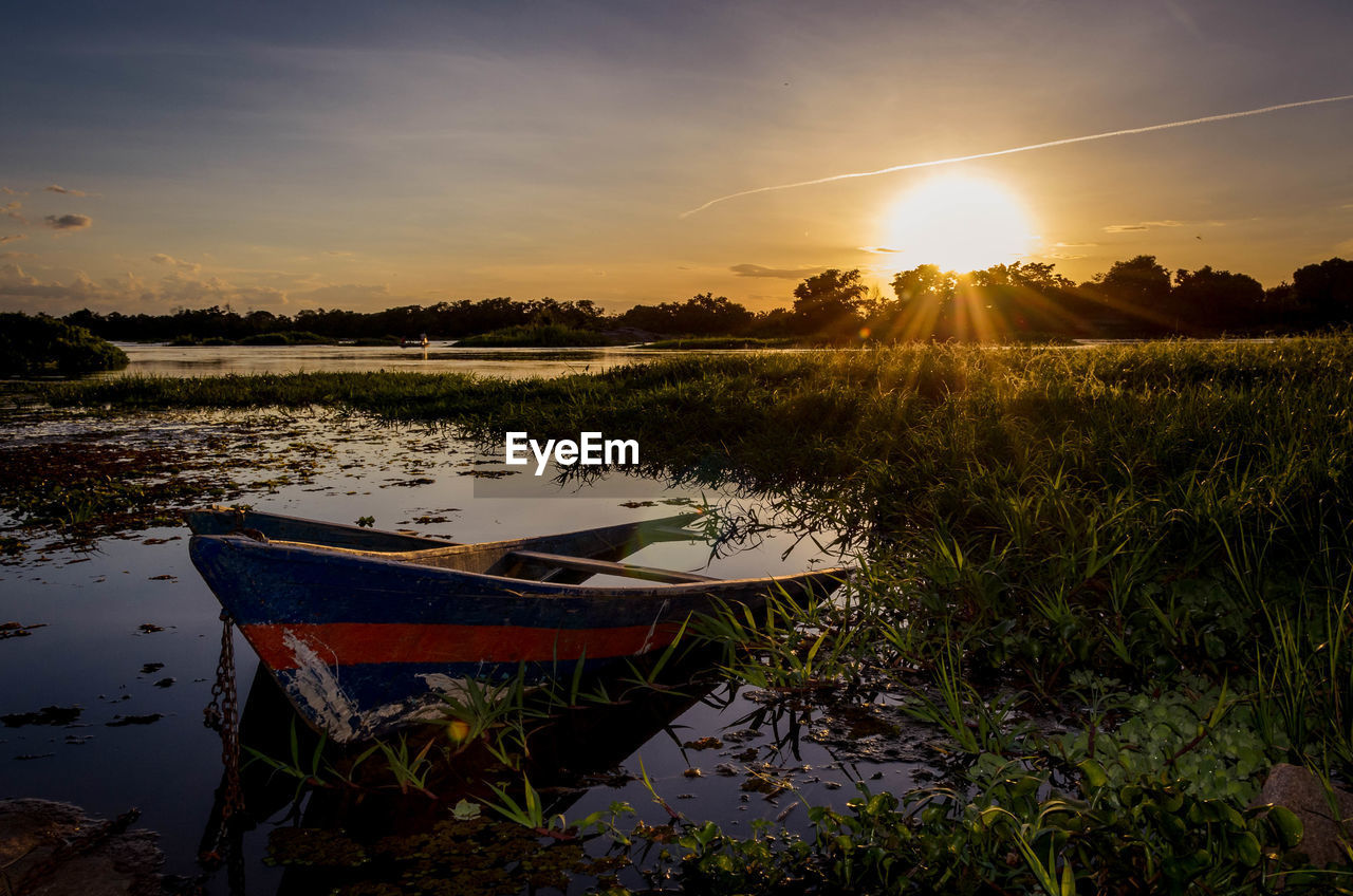 Abandoned boat in lake against sky during sunset