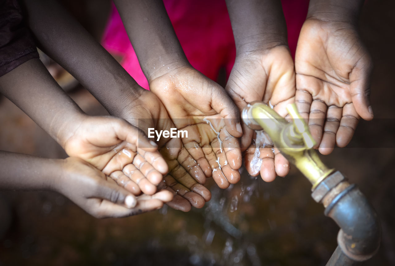 HIGH ANGLE VIEW OF HANDS HOLDING PEOPLE