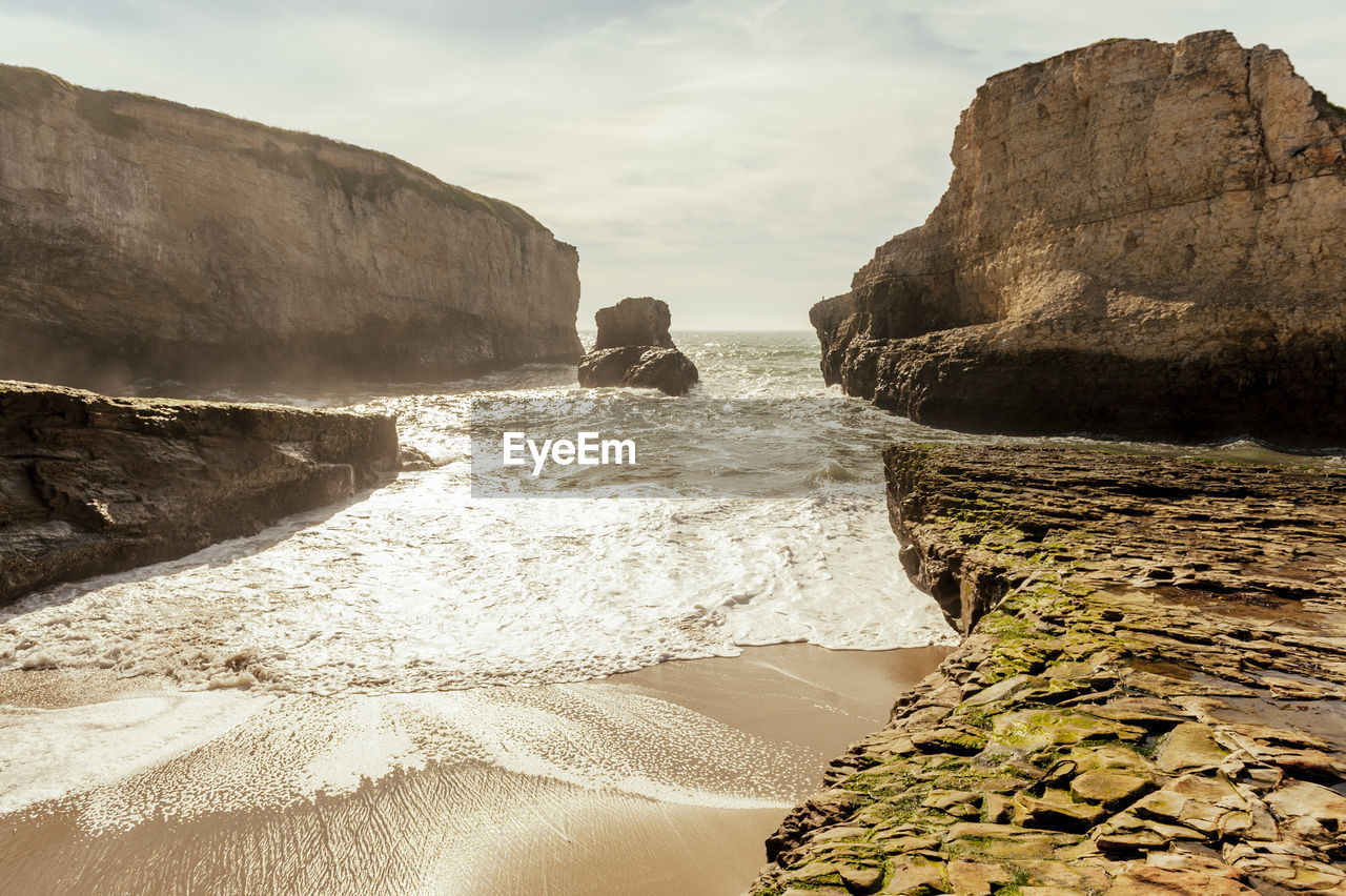 Rock formations on beach against sky