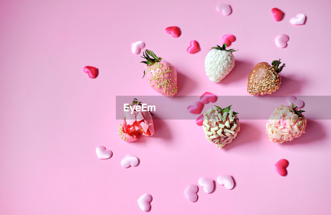 Strawberries in chocolate with scattered hearts on a pink background. sweet gift for valentine's day