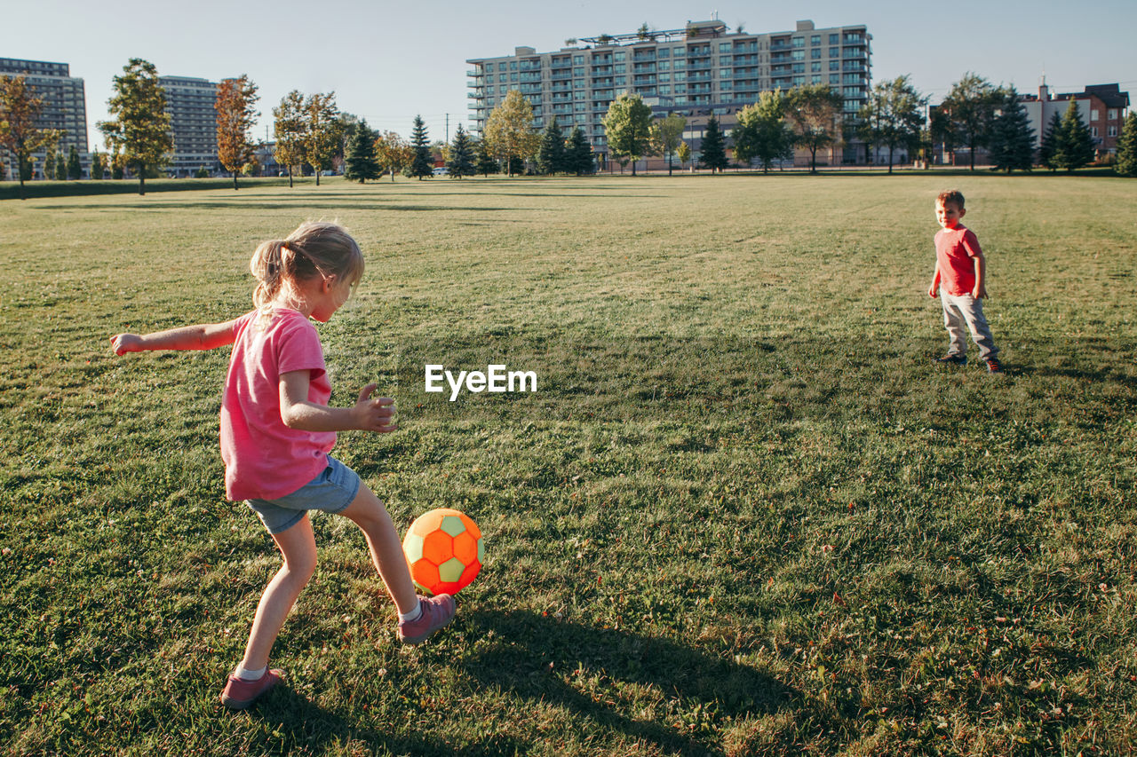 Children playing with ball on grassy land in park