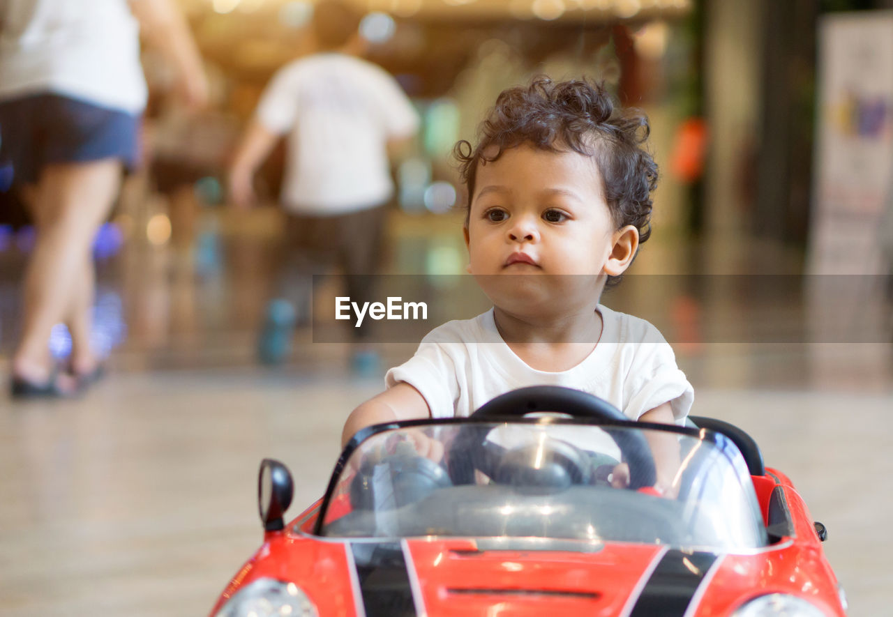 Close-up of cute boy riding toy car