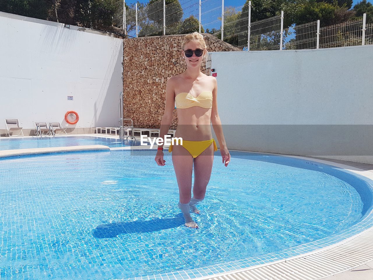 Portrait of woman wearing bikini standing in swimming pool