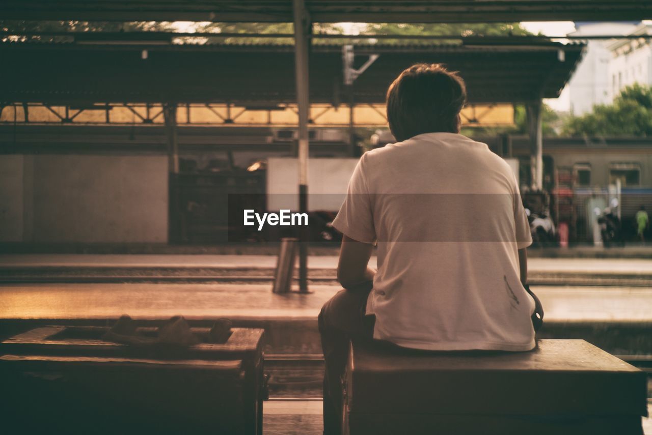 Rear view of man sitting on seat at bangkok railway station