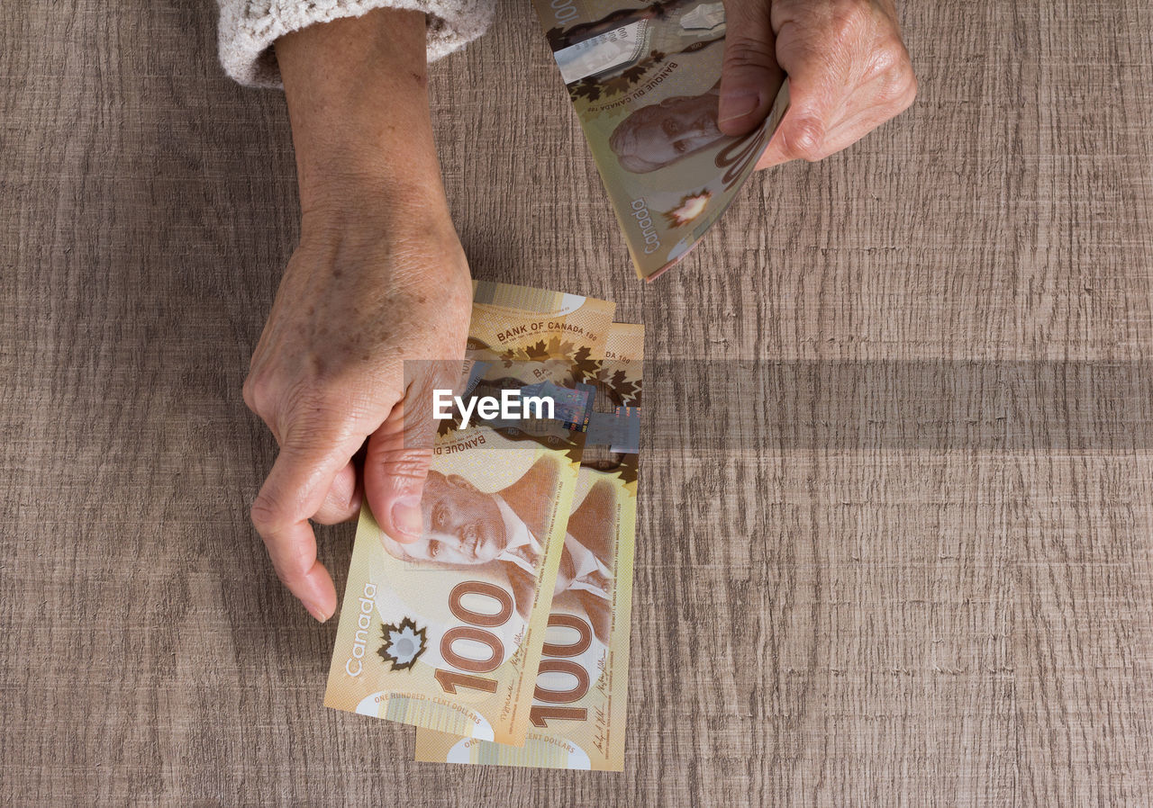 Cropped hands of woman counting money on wooden table