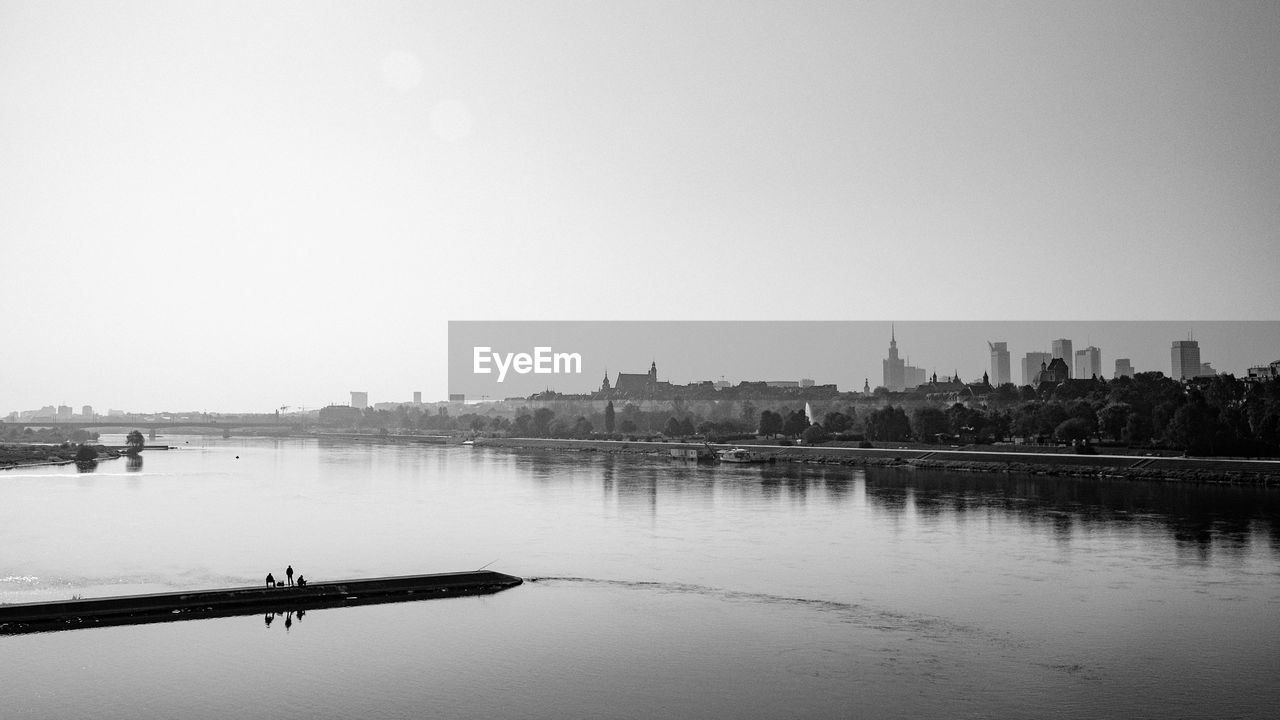 SCENIC VIEW OF RIVER BY CITY AGAINST CLEAR SKY