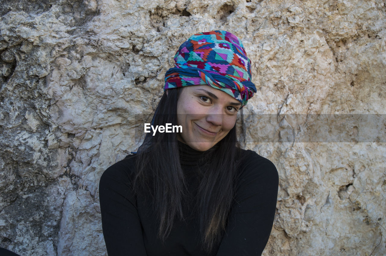 Portrait of smiling woman against rock