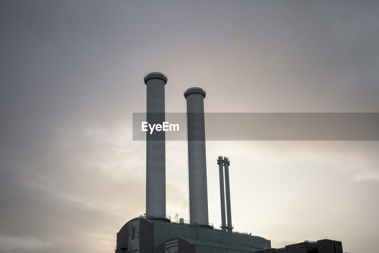 Low angle view of smoke emitting from chimney against sky