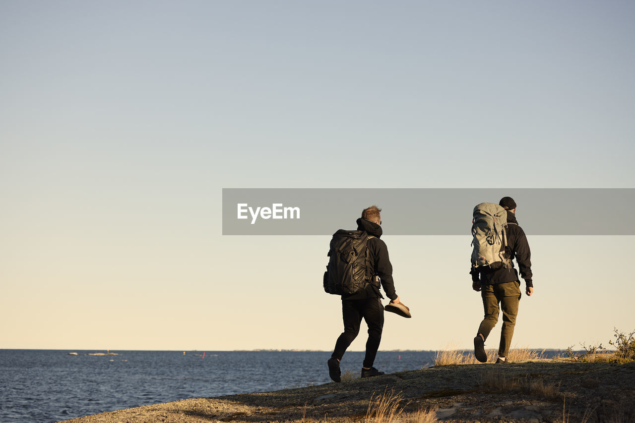 View of backpackers walking at sea