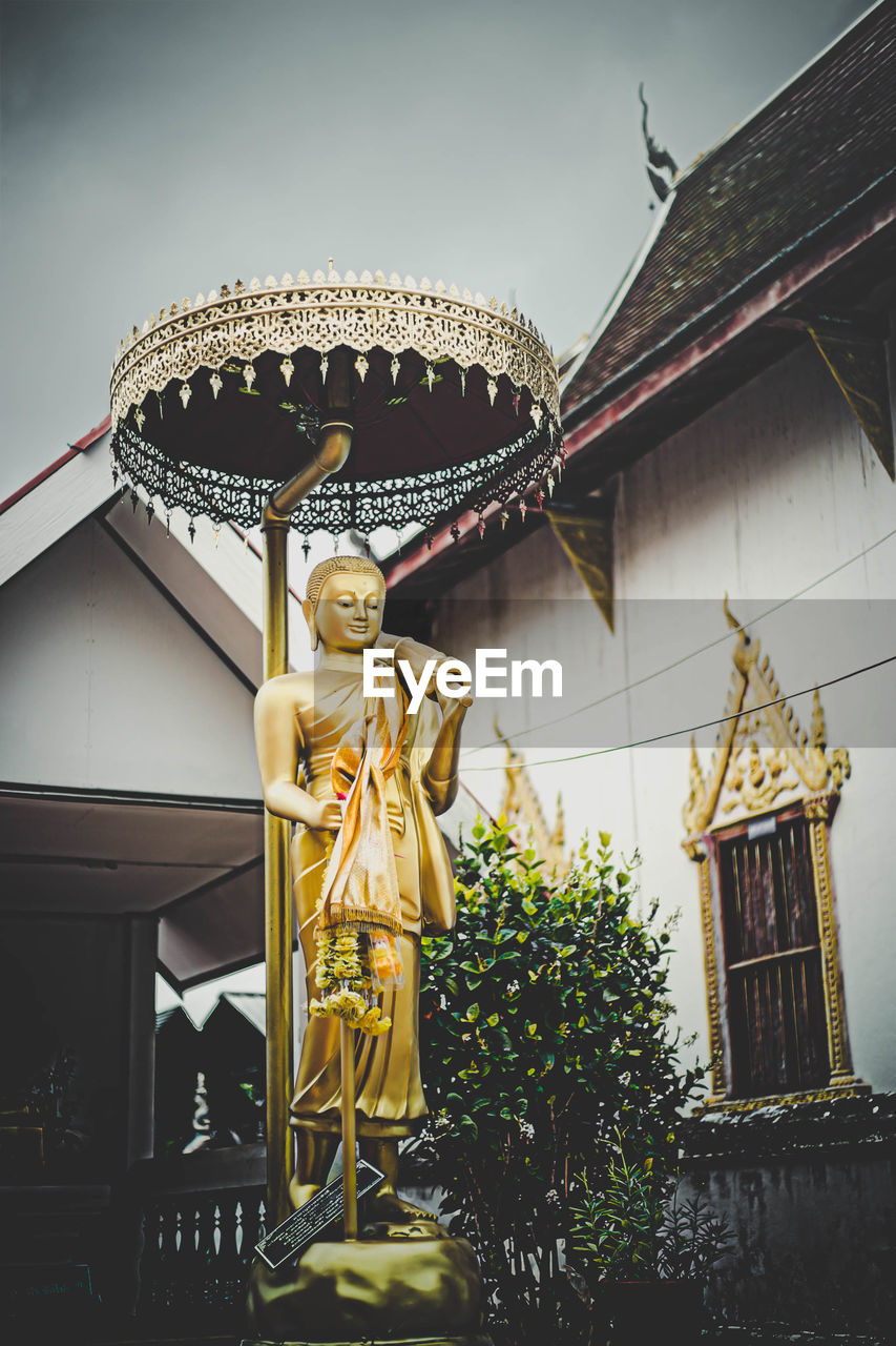 LOW ANGLE VIEW OF STATUE AGAINST BUILDING AND TEMPLE