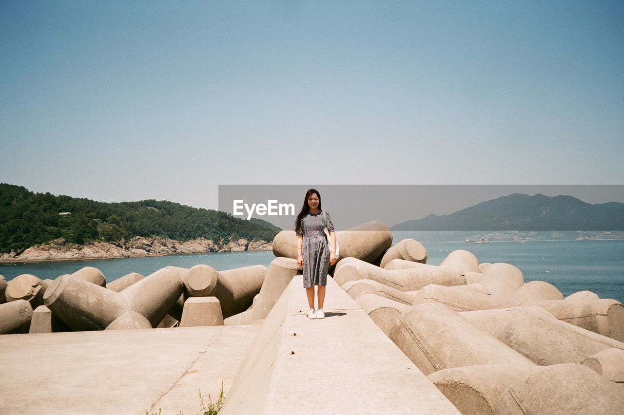 Woman standing on pier by sea against sky