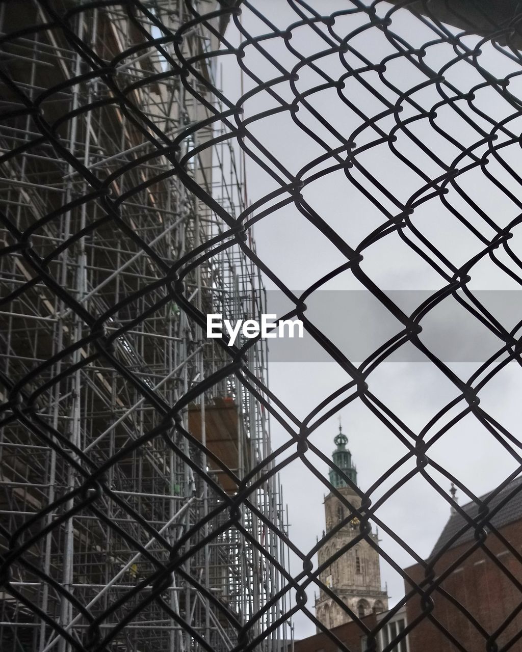 LOW ANGLE VIEW OF CHAINLINK FENCE AGAINST BUILDINGS IN CITY
