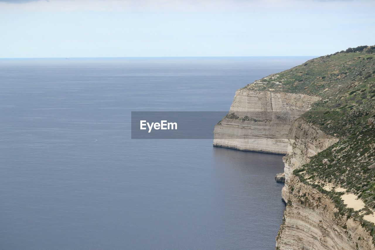 Scenic view of sea by cliff against sky