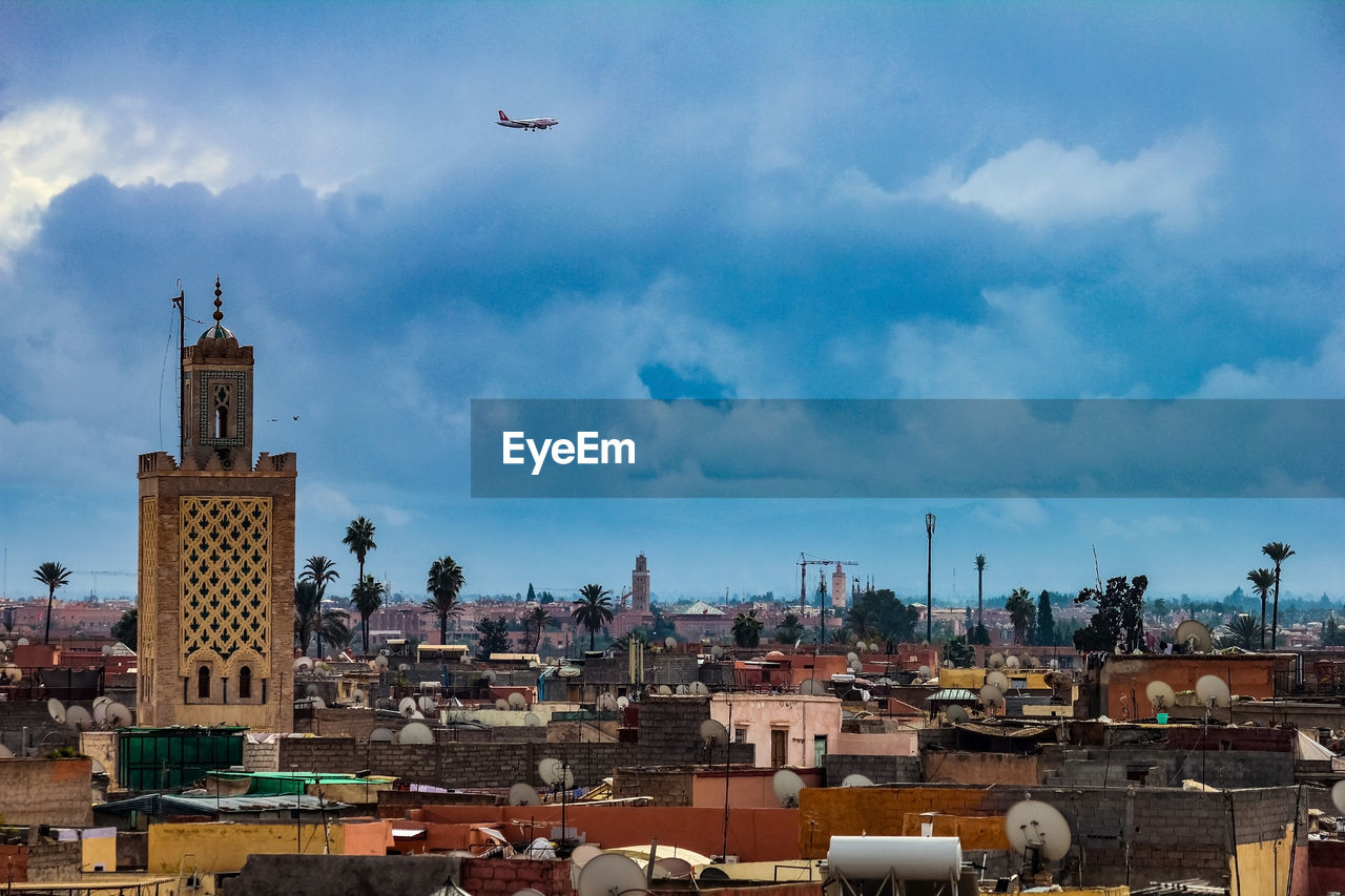 AIRPLANE FLYING OVER BUILDINGS IN CITY