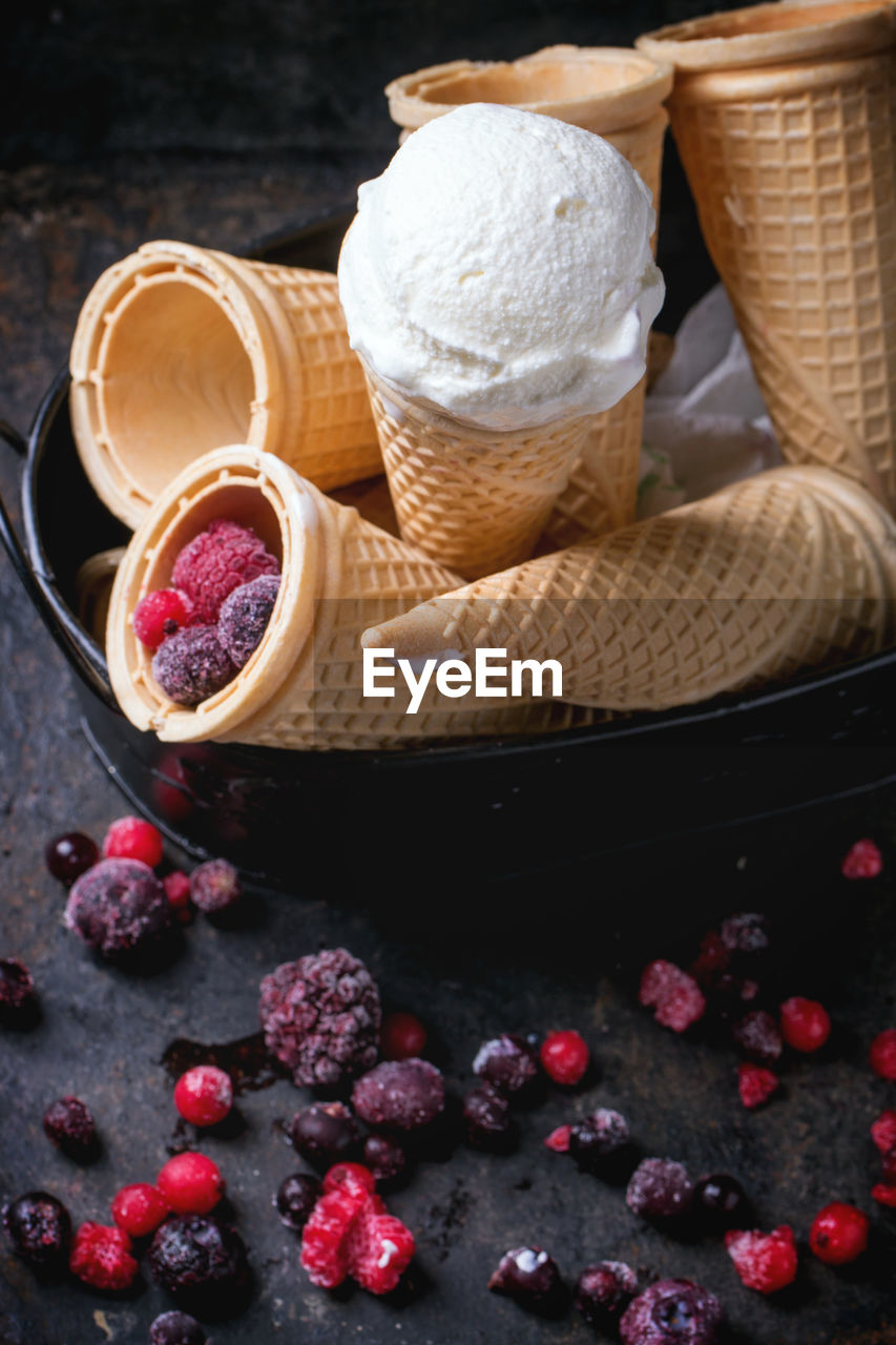 High angle view of ice cream cones by frozen berries on table