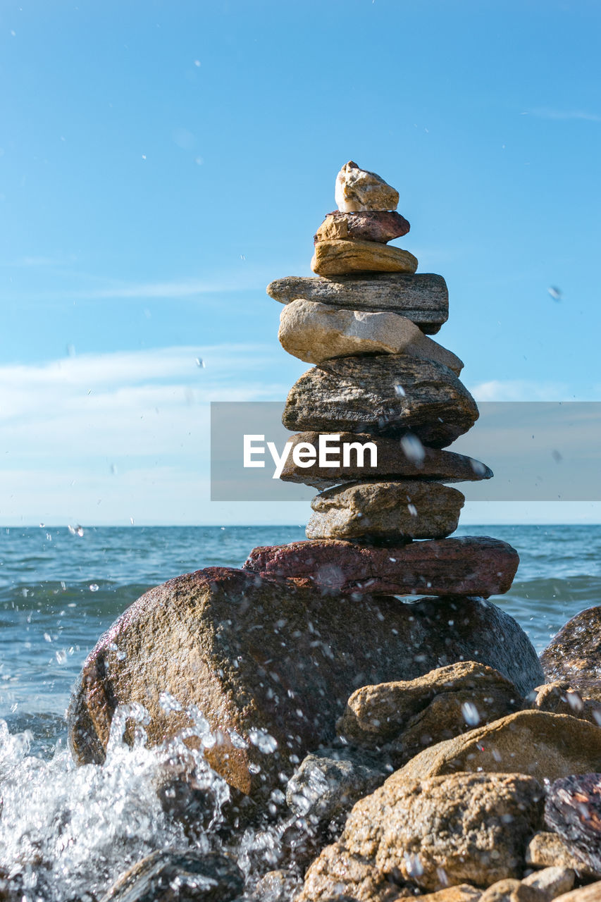 Pyramid of stacked stones on inshore waves, stability, balance and harmony concept, vertikal image