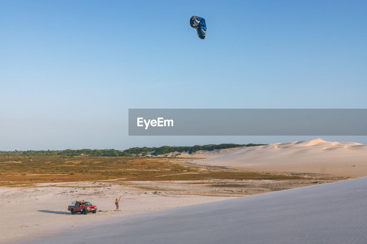 Man kiteboarding at beach against clear sky