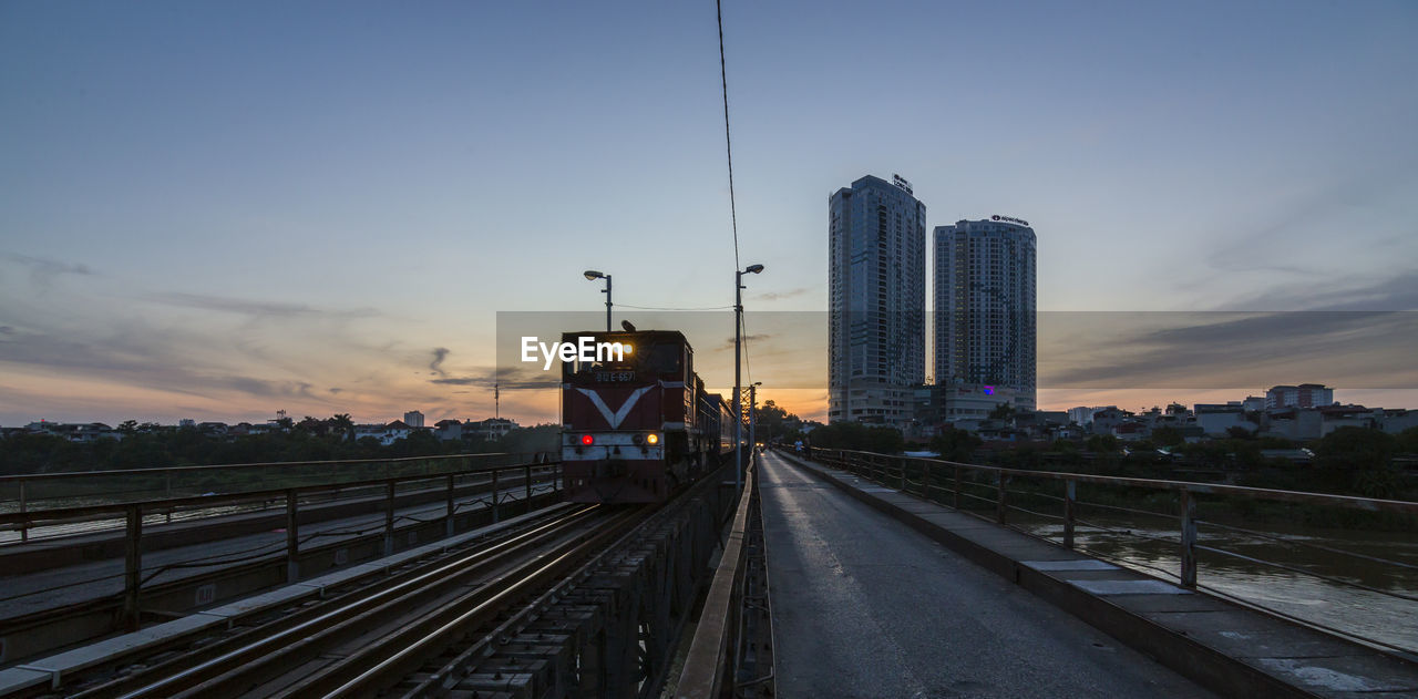 Railroad tracks in city against sky during sunset