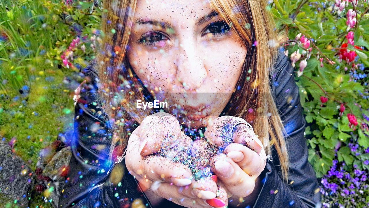 High angle portrait of woman blowing glitter