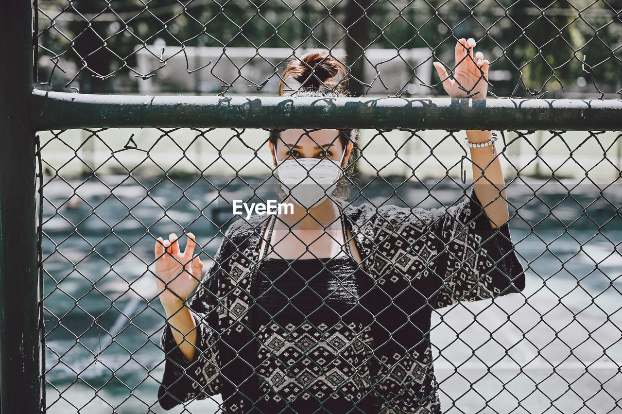 Young women wear surgical protection mask behind the cage