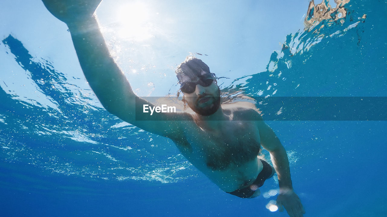 Boy swims freestyle in the open ocean.