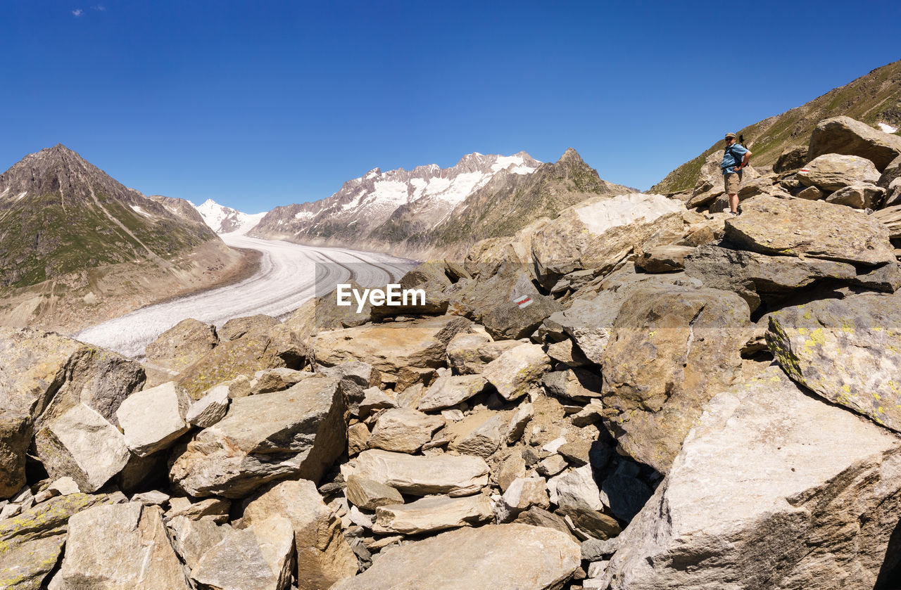 View of rocks and glacier in mountains against clear blue sky