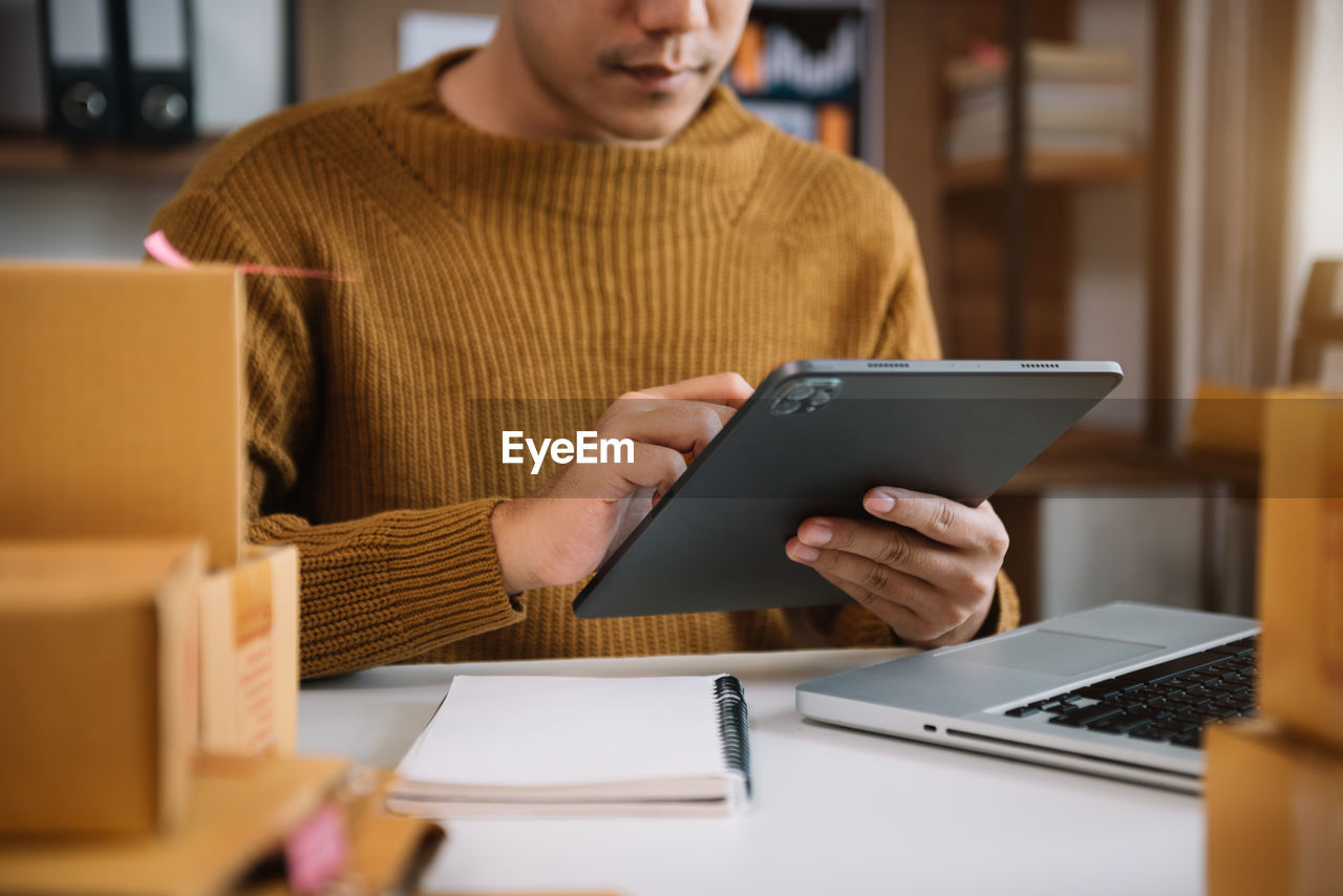 Midsection of man using digital tablet at office