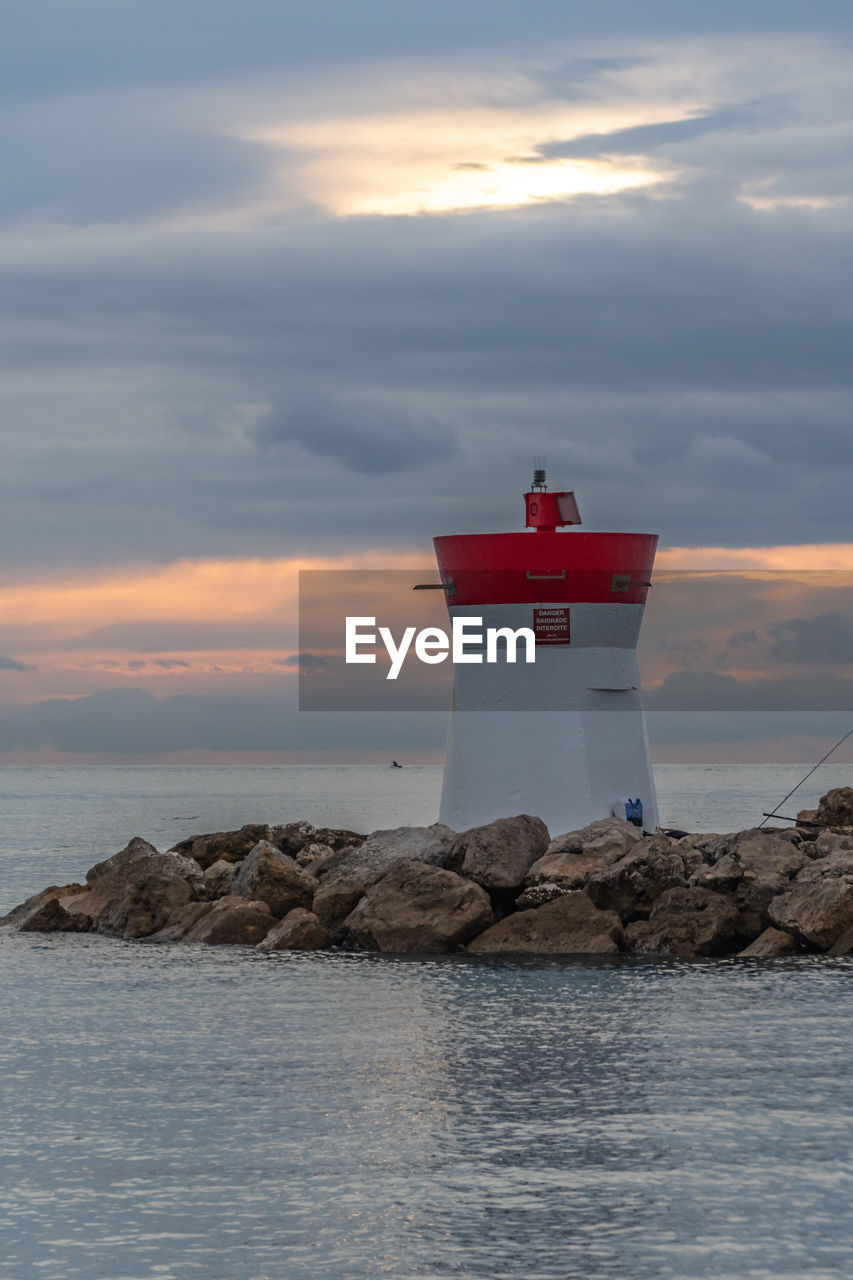 LIGHTHOUSE ON ROCK BY SEA AGAINST SKY