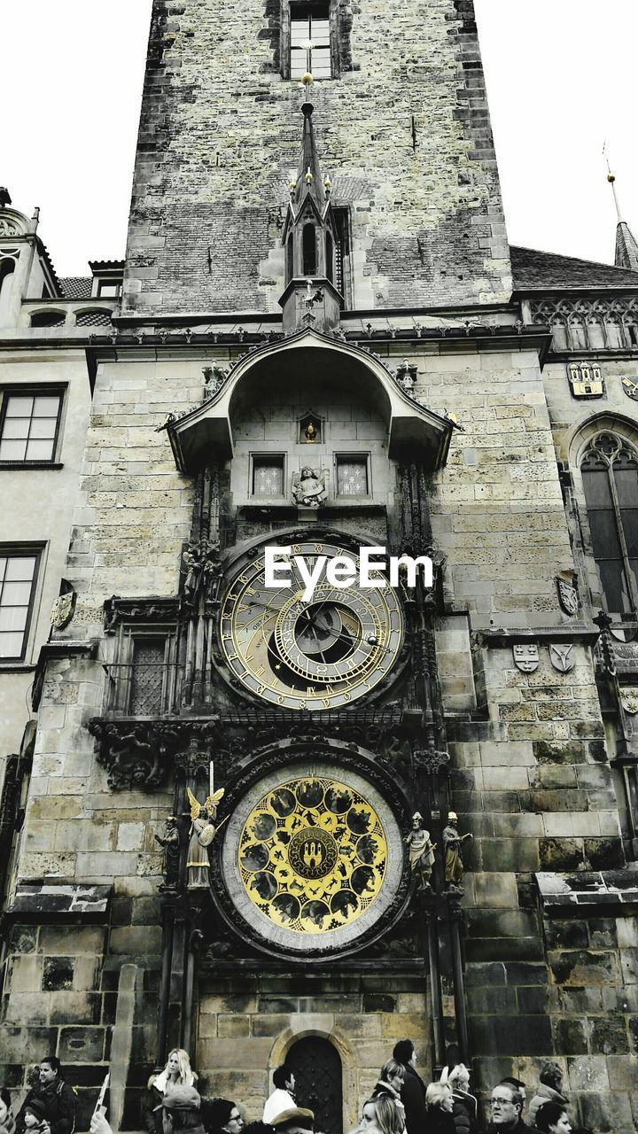 LOW ANGLE VIEW OF CLOCK TOWER WITH BUILDINGS IN BACKGROUND