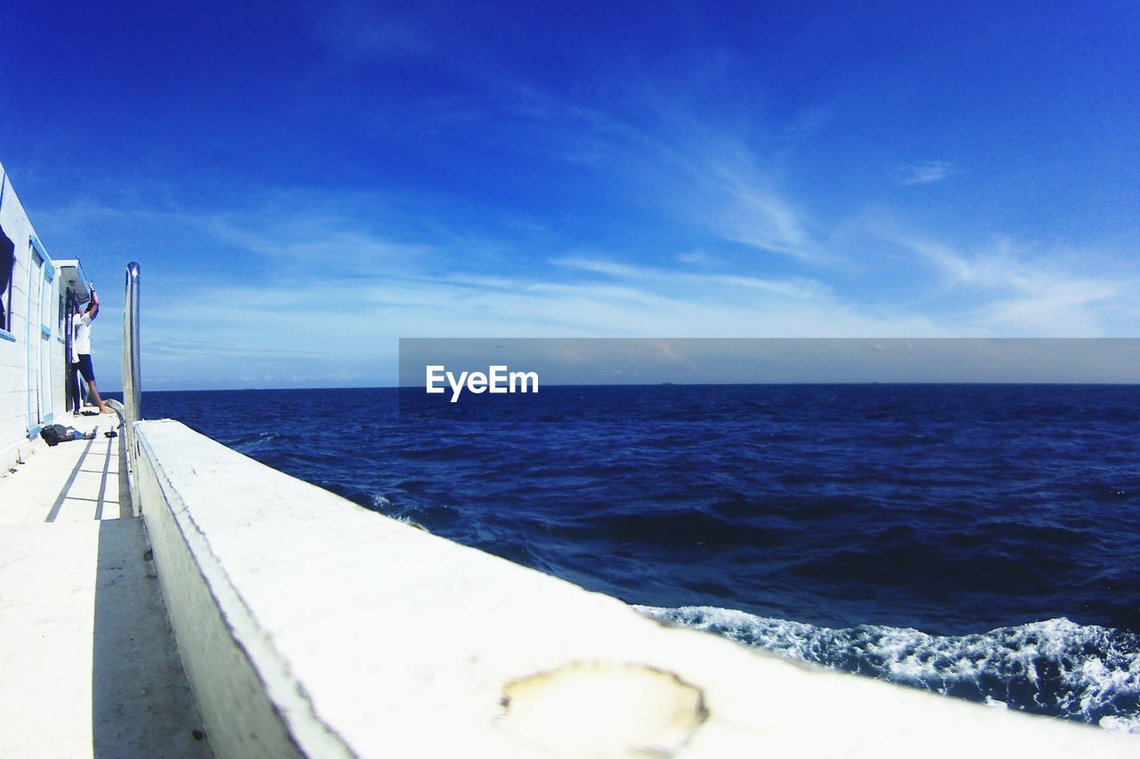 Man standing in boat on sea against sky