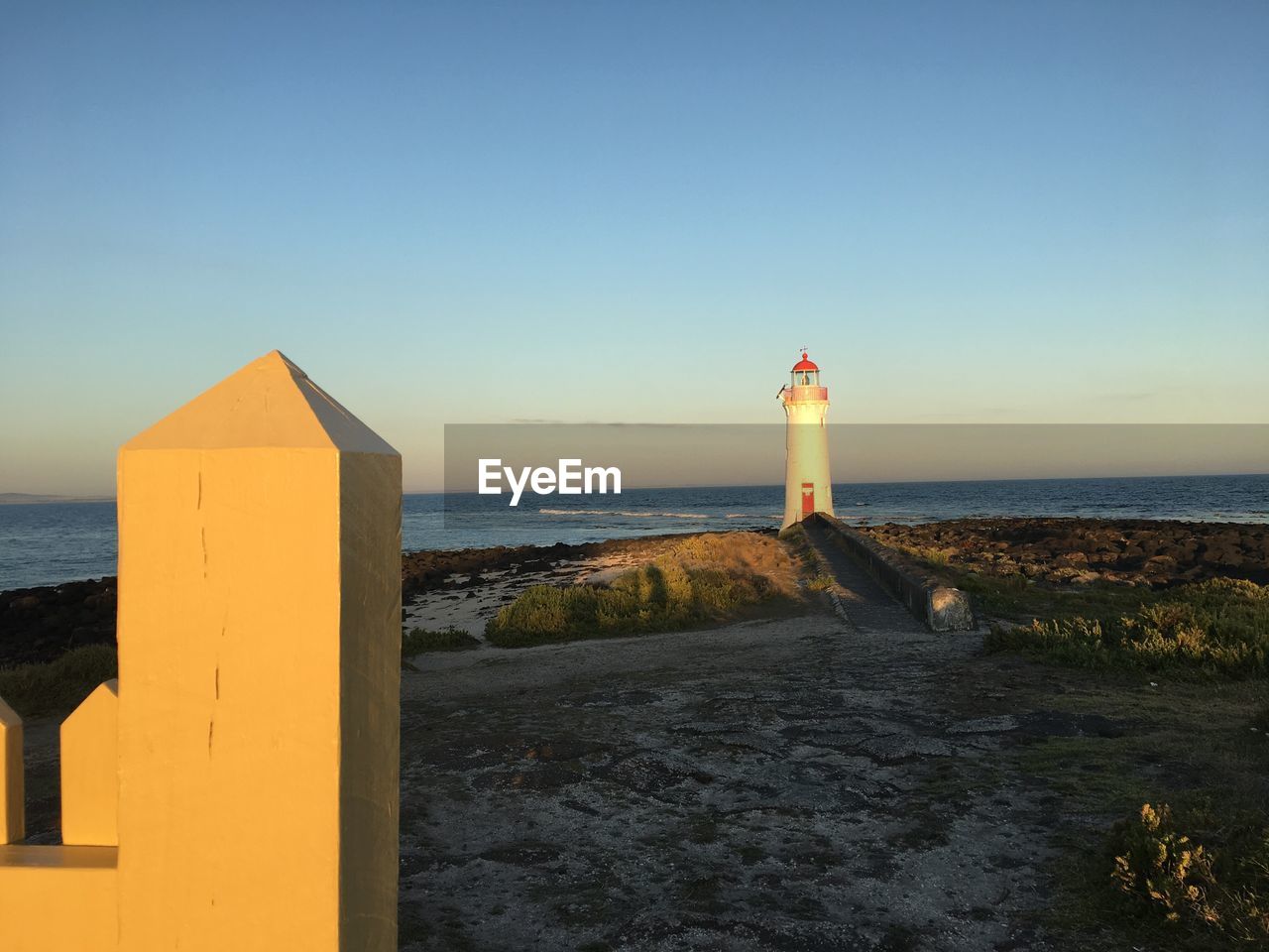 LIGHTHOUSE AMIDST SEA AGAINST CLEAR BLUE SKY