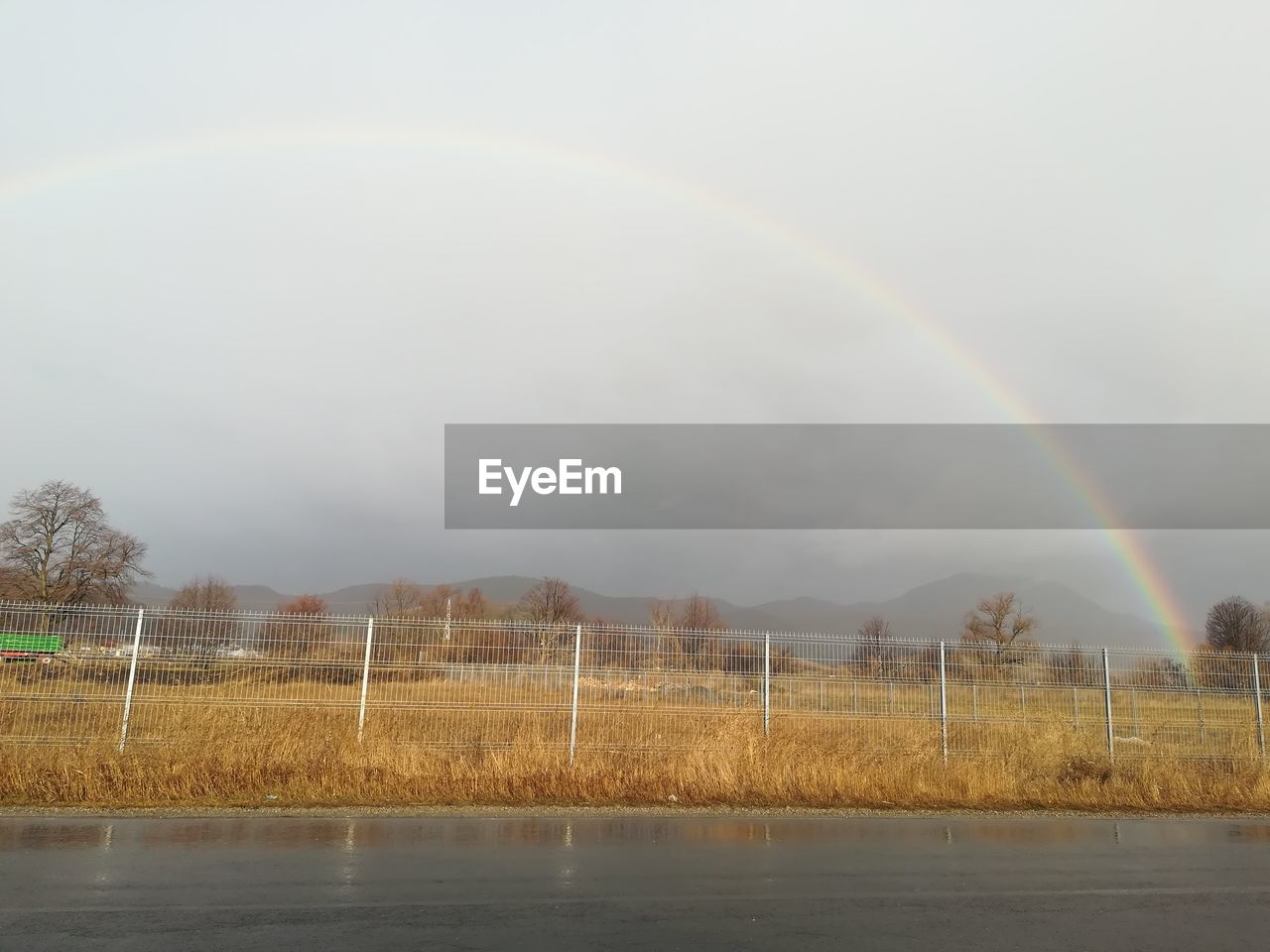 RAINBOW OVER FIELD AGAINST SKY