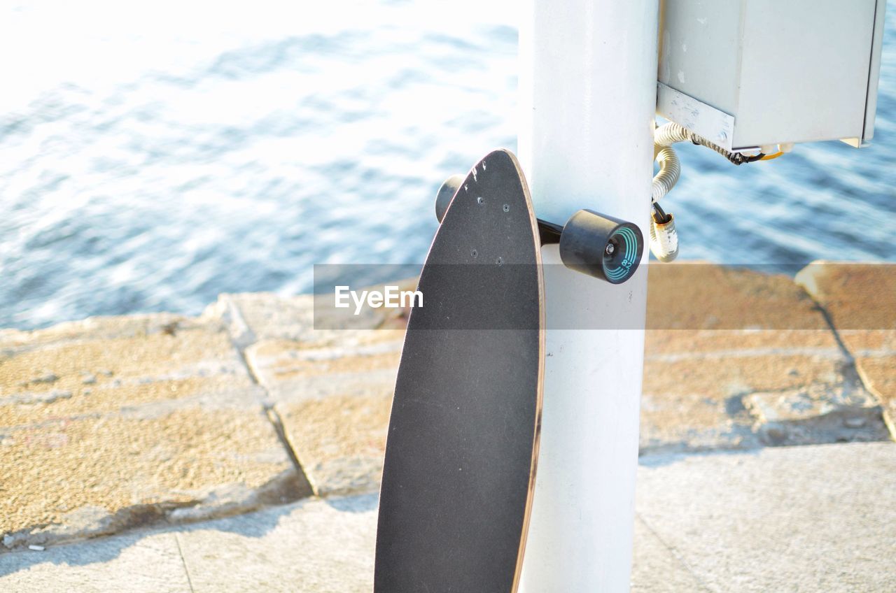 High angle view of skateboard leaning on pole by lake