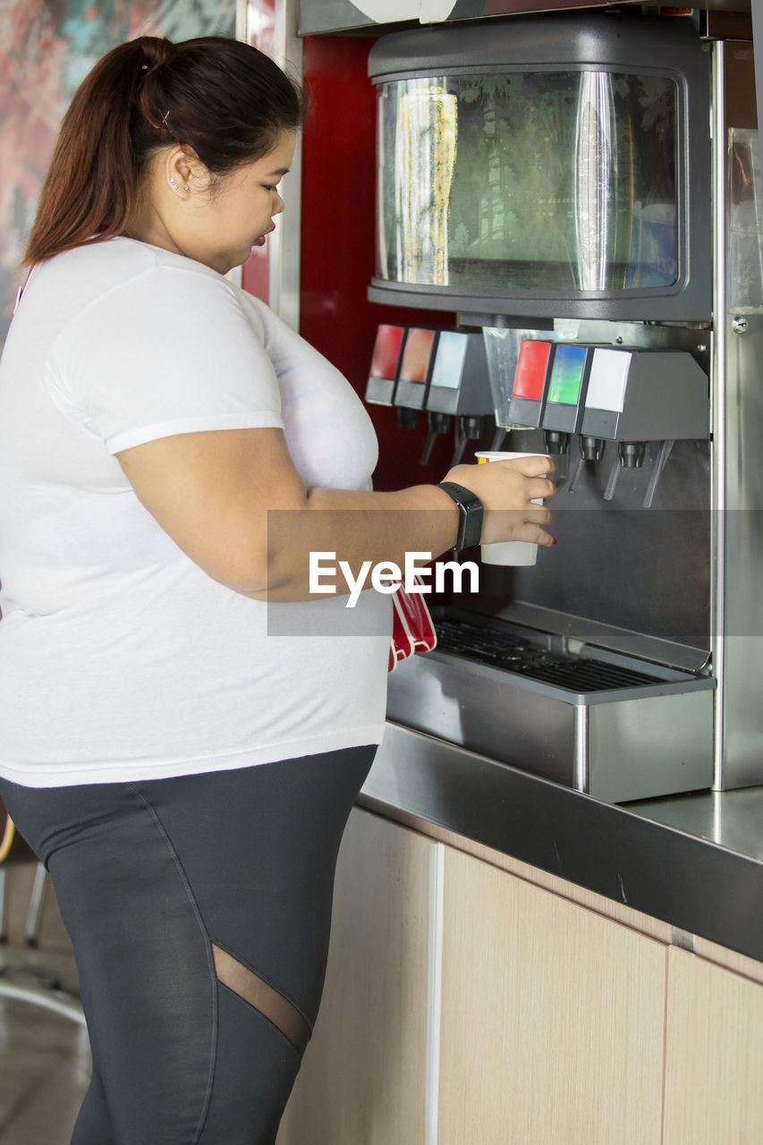 Woman standing by drink dispensing machine