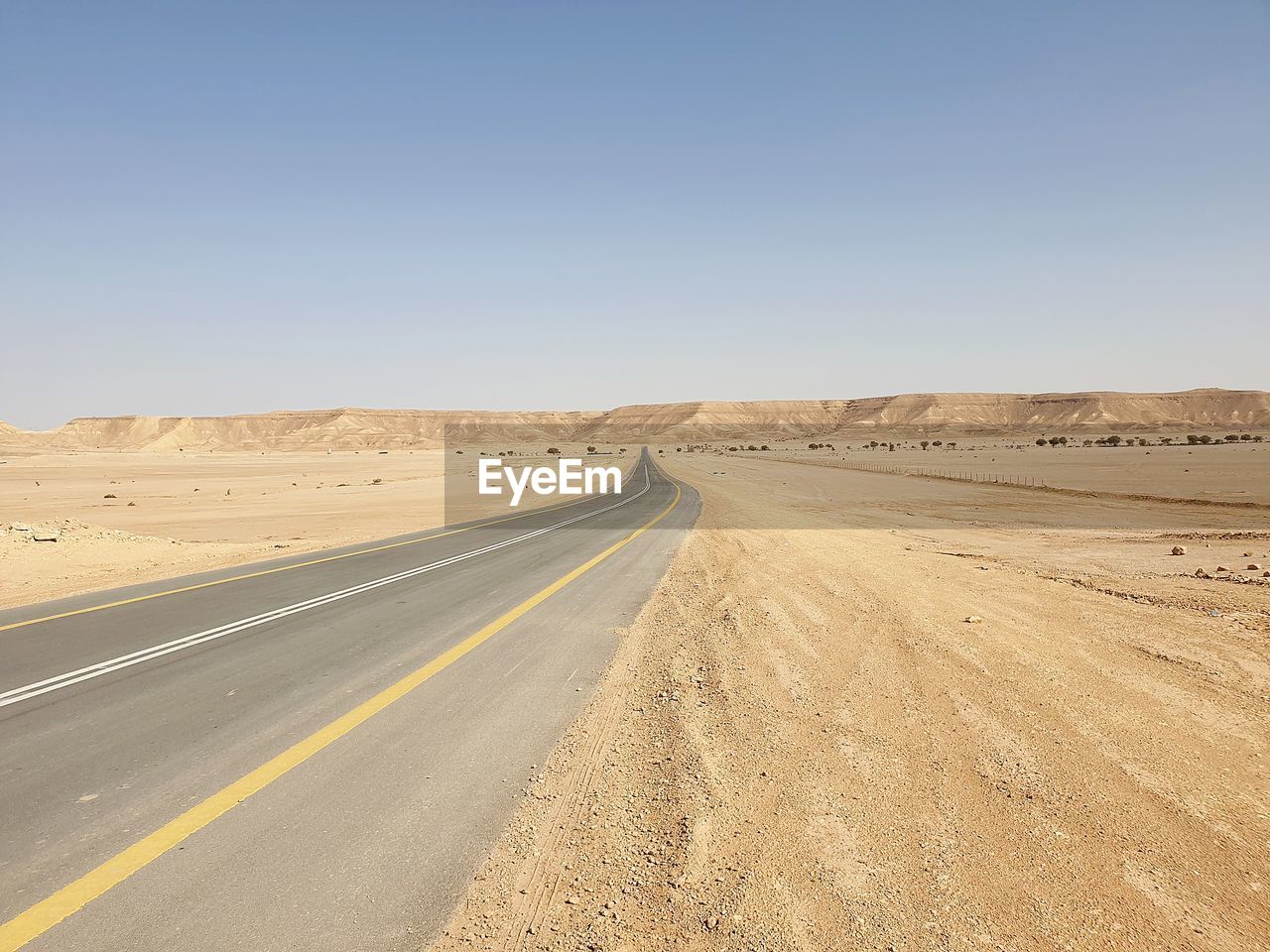 Road amidst desert against clear sky