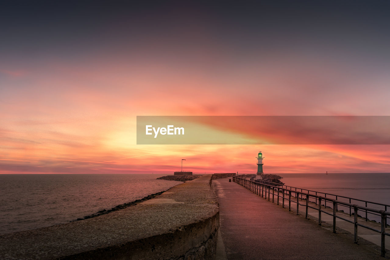 Pier on sea against sky during sunset