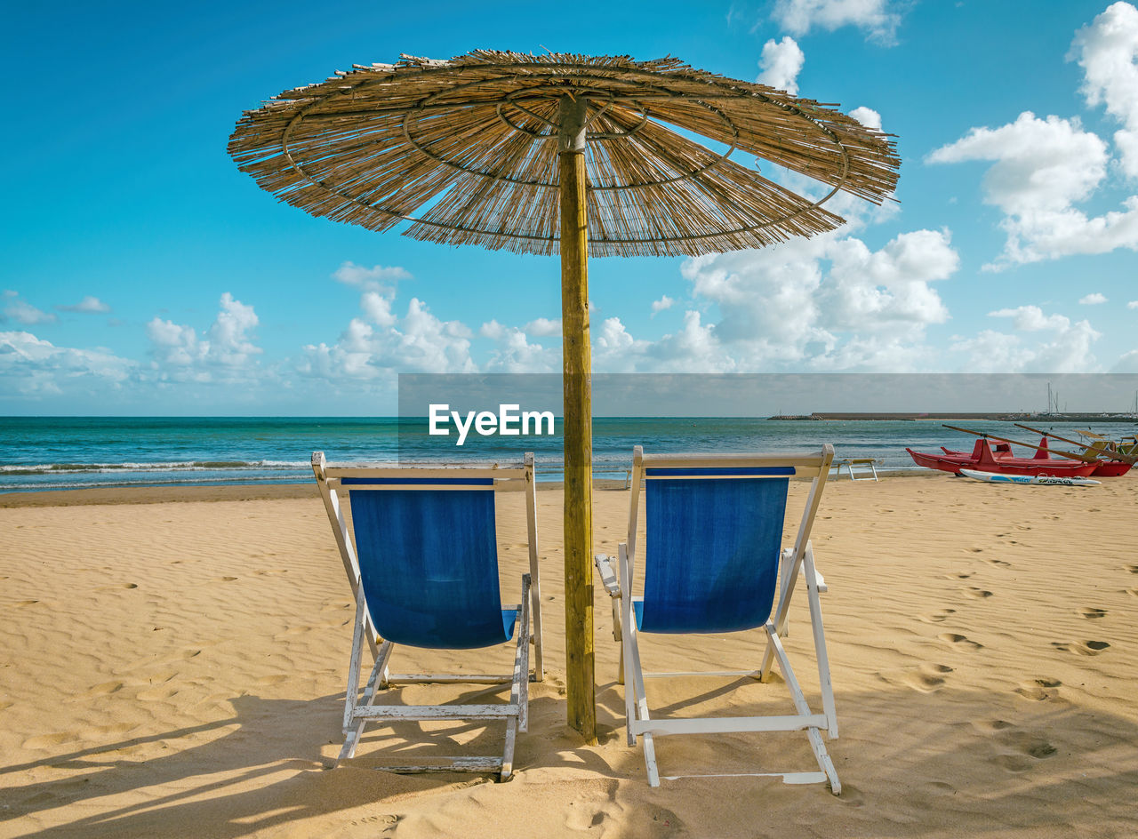 Scenic view of beach chairs on sandy beach