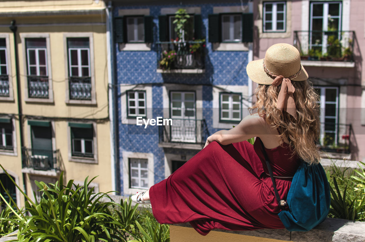 Woman sitting against buildings