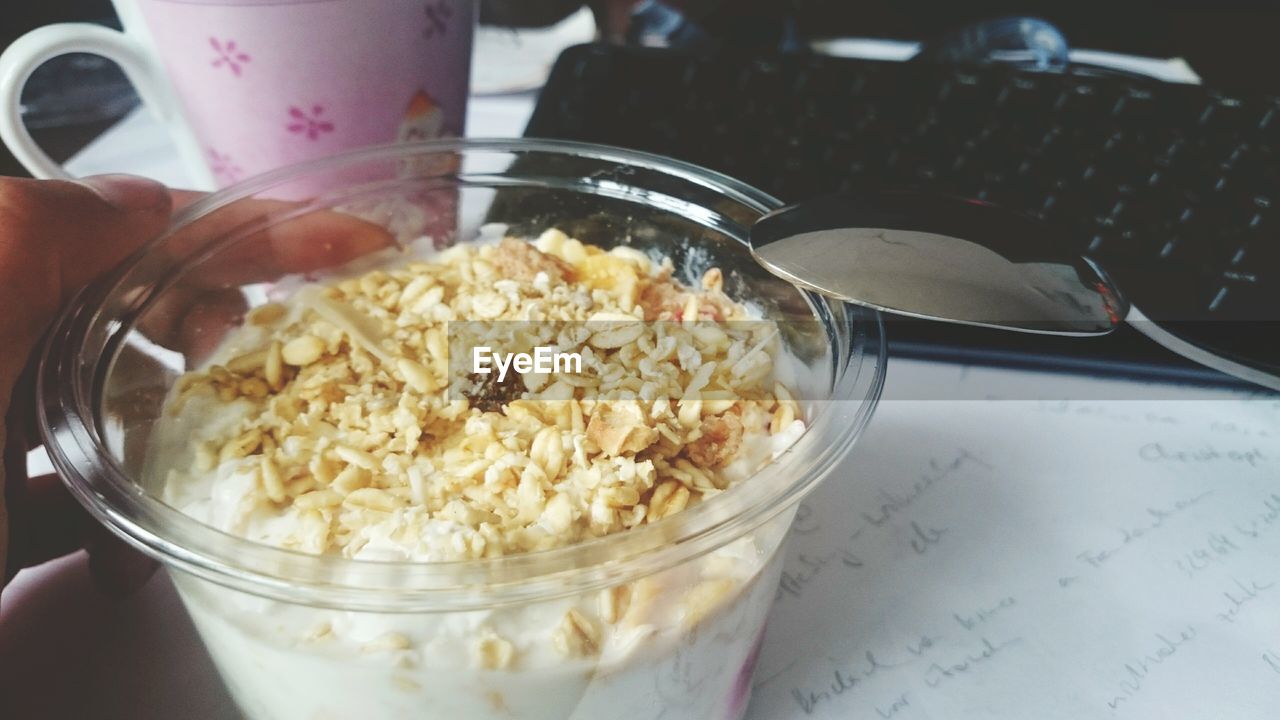 High angle view of fresh muesli and yogurt in glass bowl on table