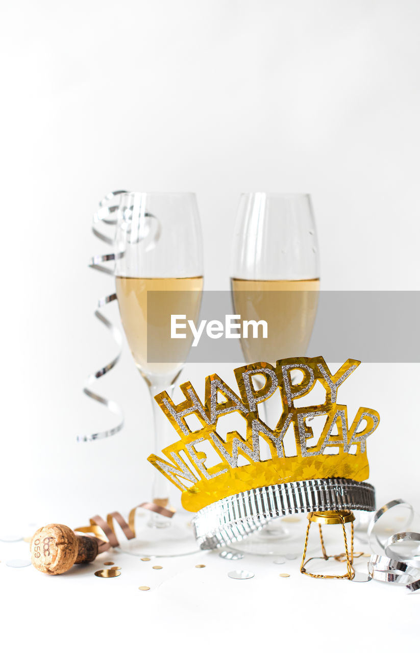 Glasses of champagne and happy new year hat on white background.