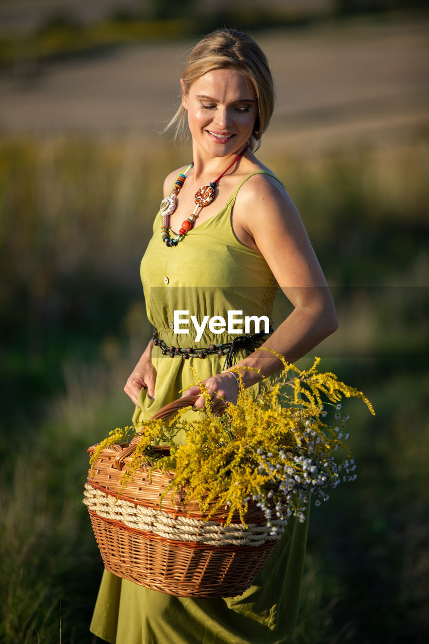 portrait of young woman standing in basket on field