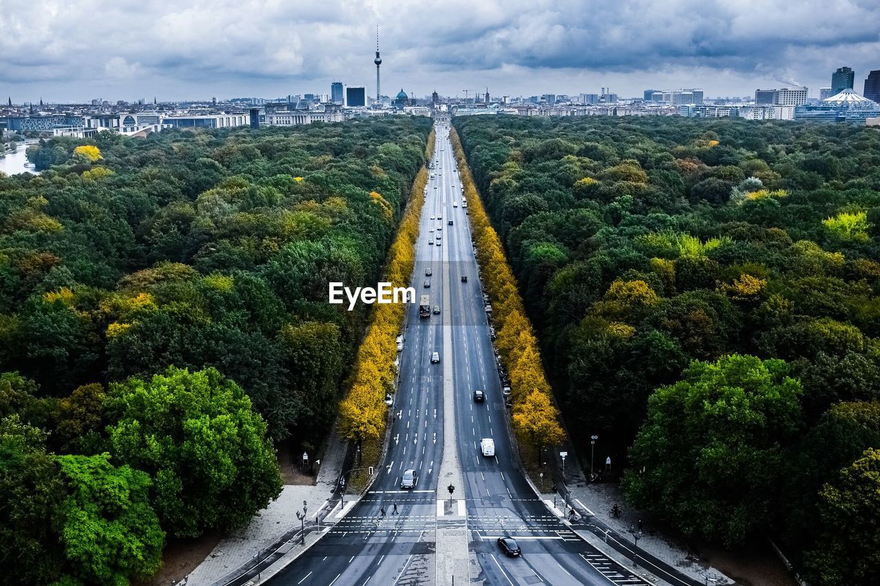 Road amidst trees in city against sky