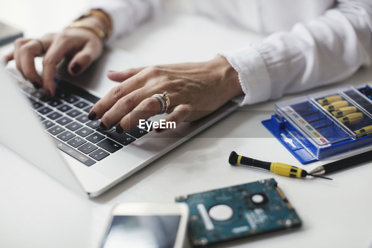 Cropped image of businesswoman using laptop on table in home office