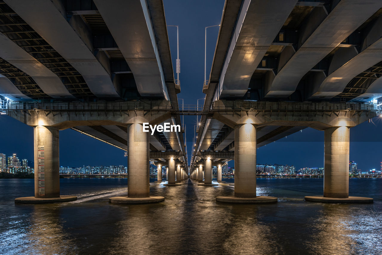 bridge over river against sky at night