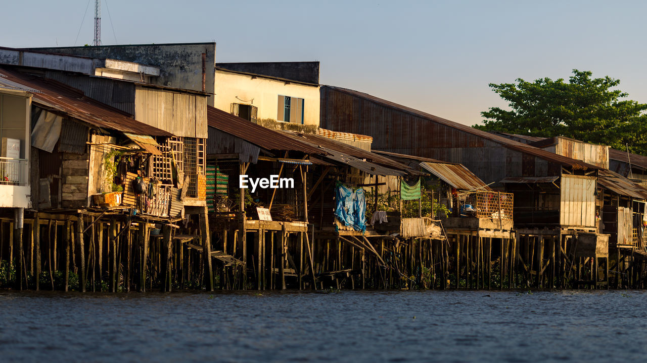 Houses by sea against clear sky during sunset