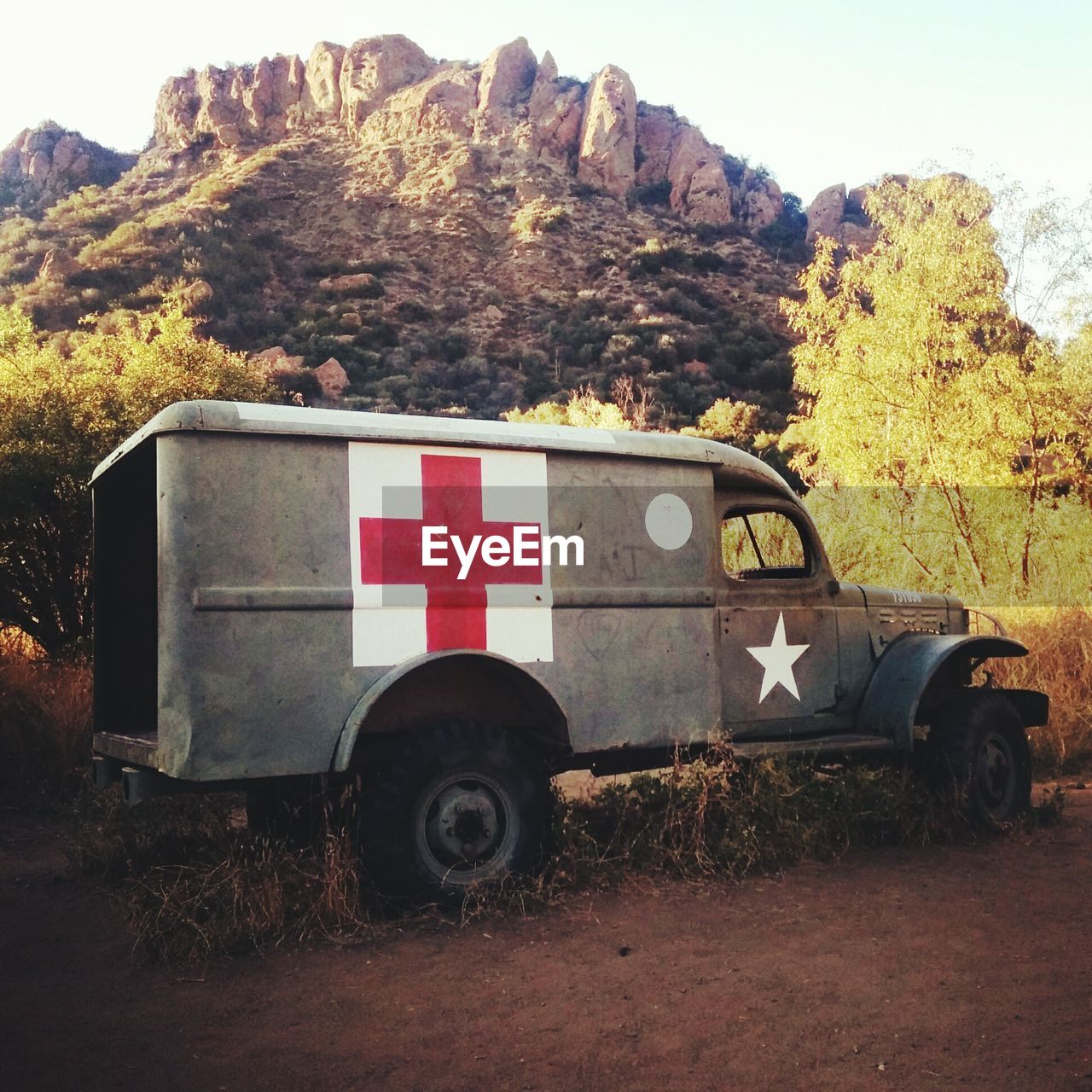 Military ambulance by rocky mountains against sky